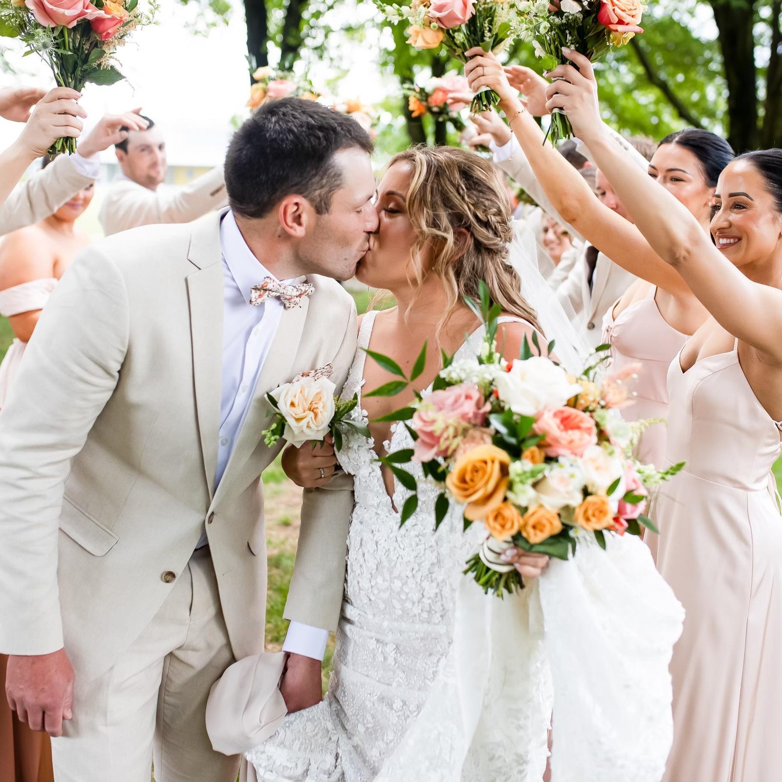 Bride and groom kissing under a bouquet arch
