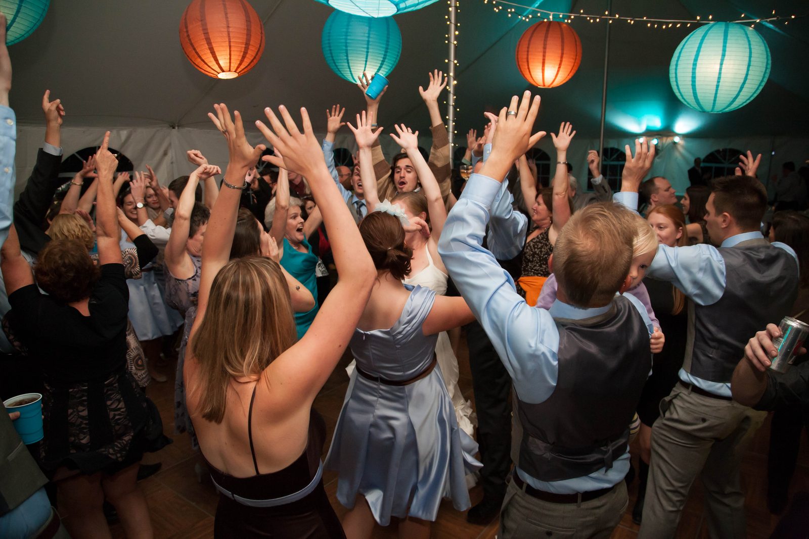 Wedding guests with hands raised under colorful paper lanterns