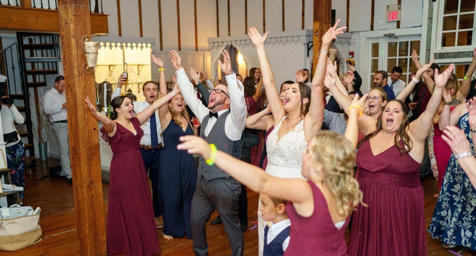 Newlyweds and wedding party cheering on the dance floor